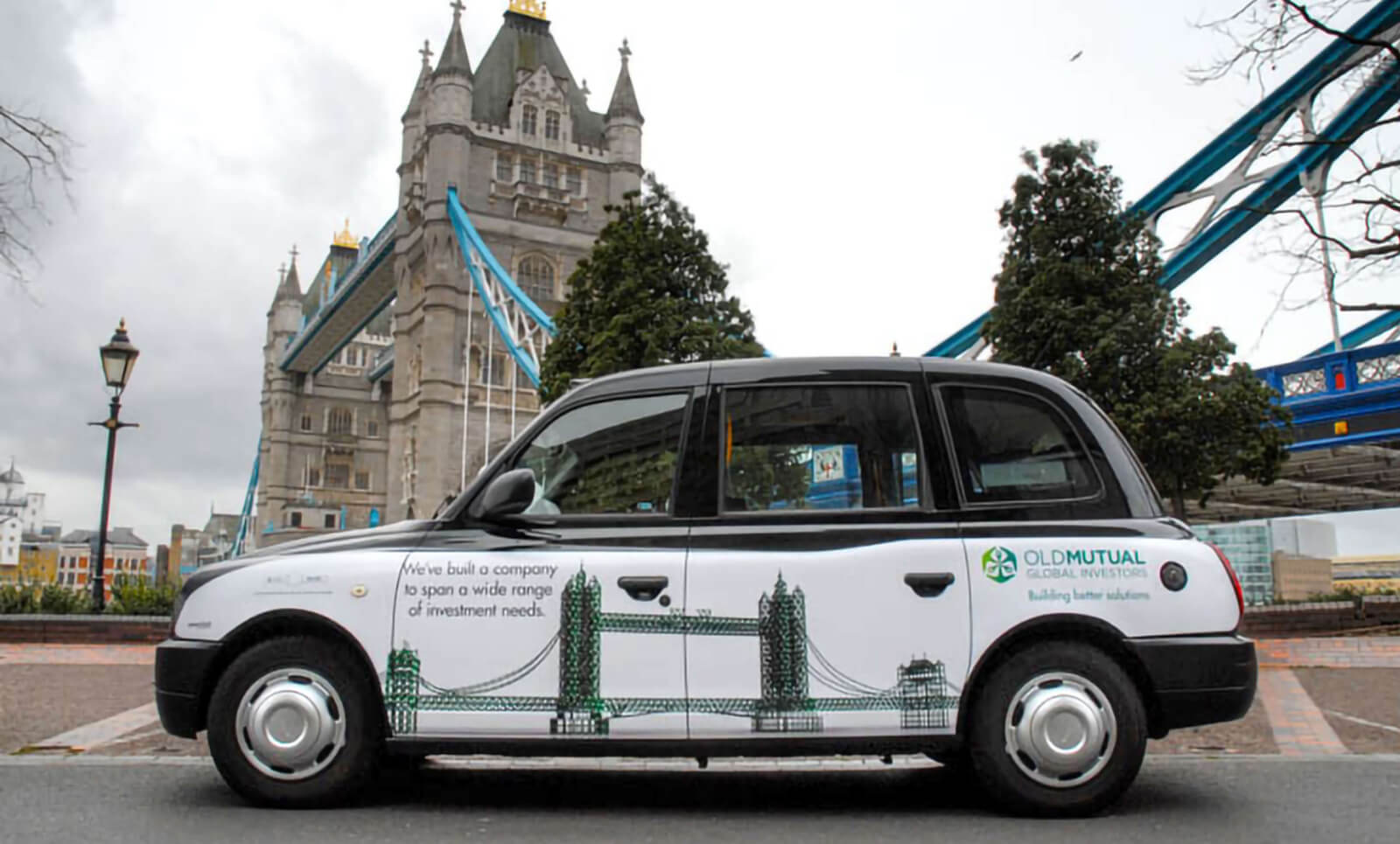 Ad on side of a London Hackney Cab parked in front of Tower Bridge